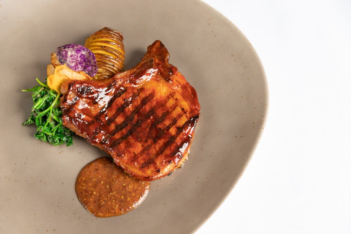 Grilled barbequed Pork chop celery root roasted Quebec potatoes apple sauce wilted spinach and mustard grain seeds